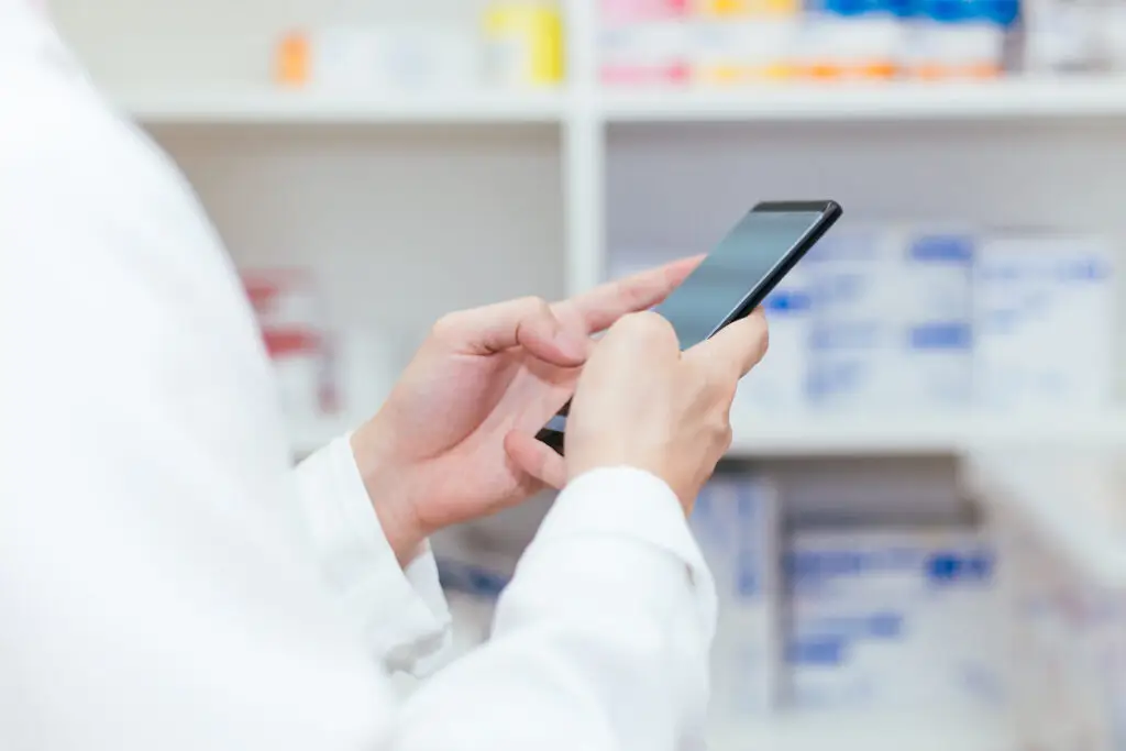 Pharmacist, Physician using a mobile phone at drugstore room. Doctor touching a cell phone in medical concept